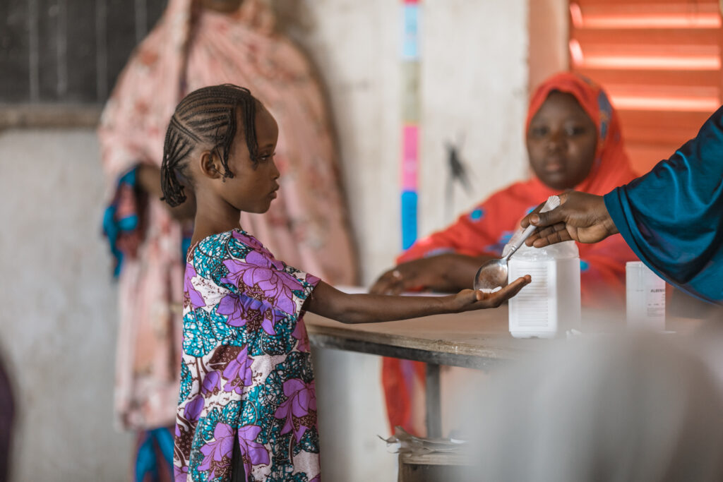 A young child receiving schistosomiasis medicine during a mass drug administration (MDA) campaign in a school in N’dounga Tarey, Niger. Credit: Speak Up Africa